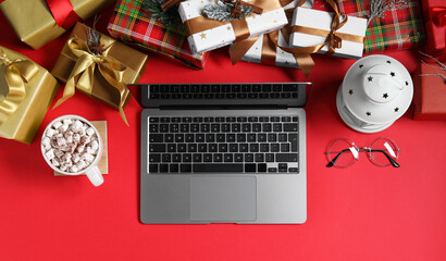 Flat lay composition with laptop, gift boxes, eyeglasses and cup of drink on red background. Letter for Santa - Powered by Adobe