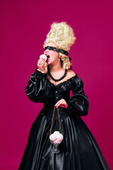 Woman, medieval person dressed in old-fashioned black dress with lace blindfold holding scales with marshmallows and eating it against magenta background.