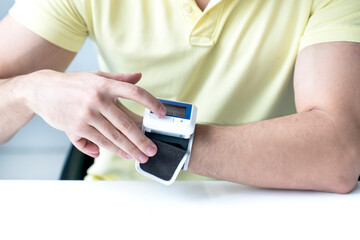 Close-up of man checks up his blood pressure and pulse by wrist tonometer
