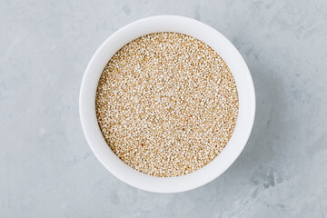 Quinoa grains. Dried quinoa seeds in bowl on gray stone background, top view.