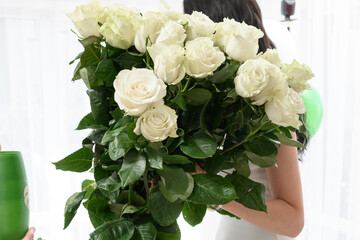 The girl holds a large bouquet of white roses in her hands.