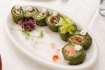 Spinach roll with cheese filling is cut and served on the table