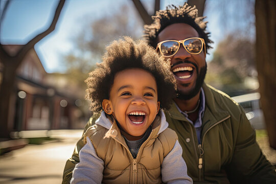 Joyful African American father and smiling toddler son bonding in sunny urban park depicting family fun and happiness - Powered by Adobe