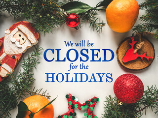 Signboard with the inscription We will be closed for the Holidays. Christmas decorations lying on...