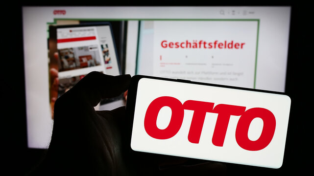 Stuttgart, Germany - 11-14-2023: Person holding mobile phone with logo of German mail order company Otto GmbH Co KG in front of business web page. Focus on phone display.