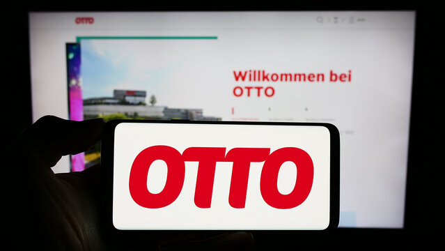 Stuttgart, Germany - 11-14-2023: Person holding cellphone with logo of German mail order company Otto GmbH Co KG in front of business webpage. Focus on phone display.