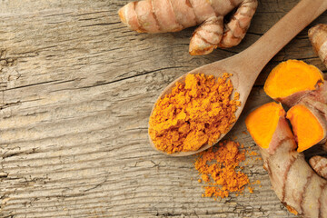 Aromatic turmeric powder and raw roots on wooden table, flat lay. Space for text