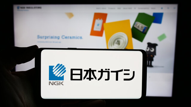 Stuttgart, Germany - 11-15-2023: Person holding smartphone with logo of Japanese ceramics company NGK Insulators Ltd. in front of website. Focus on phone display.