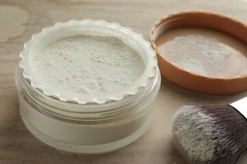 Rice loose face powder and makeup brush on brown table, closeup