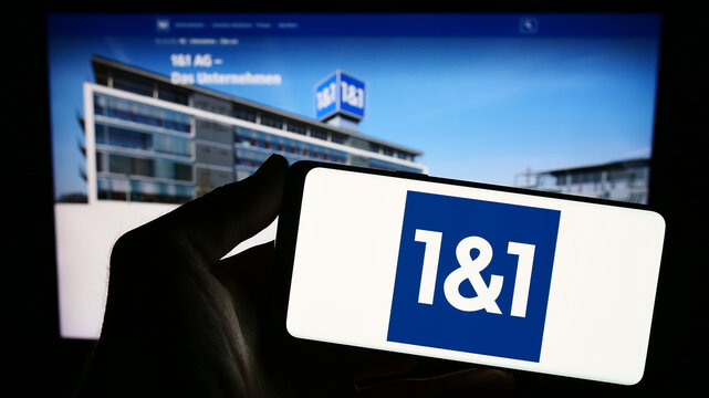 Stuttgart, Germany - 11-15-2023: Person holding smartphone with logo of German company 1und1 Telecommunication SE in front of website. Focus on phone display.