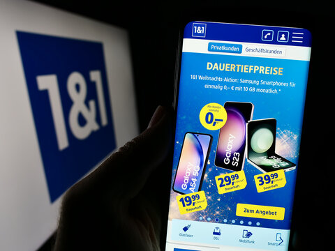 Stuttgart, Germany - 11-15-2023: Person holding cellphone with webpage of German company 1und1 Telecommunication SE in front of business logo. Focus on center of phone display.