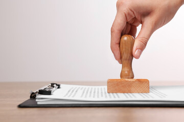 Woman stamping documents at wooden table, closeup. Space for text