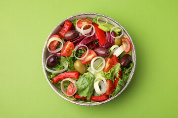 Bowl of tasty salad with leek and olives on light green table, top view