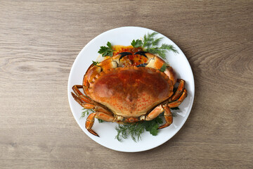 Delicious crab with greens on wooden table, top view