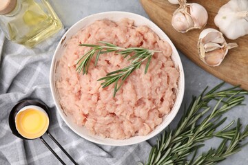 Flat lay composition with fresh raw minced meat and rosemary on light grey table