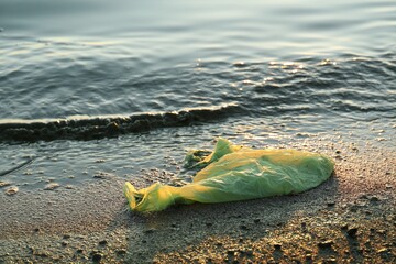 Used plastic bag near water at beach. Environment pollution