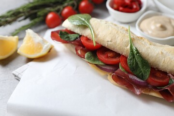 Delicious sandwich with bresaola, tomato, onion and cheese on table, closeup. Space for text