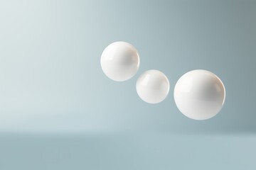  three white balls floating in the air on a gray and light blue background, with one white ball in the foreground and one white ball in the foreground.
