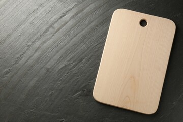 One wooden cutting board on dark grey table, top view. Space for text