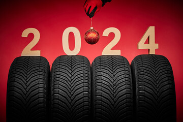 Winter car tires and man hand in red gloves hold christmas tree ball, 2024 happy new year background