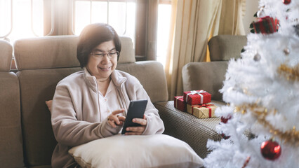 Asian elder woman lifestyle with modern technology using mobile phone on christmas holidays