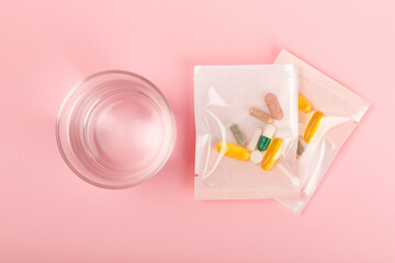 Vitamins and supplements. Variety of vitamin tablets with a glass of water on a texture background. Multivitamin complex for every day. Nutritional supplements. It's time to take your pills. Flat lay.