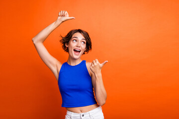 Photo of impressed excited girl dressed blue top looking pointing two thumbs empty space isolated...