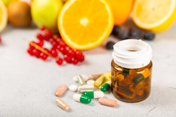 Vitamins and supplements. Variety of vitamin tablets in a jar on a texture background.Multivitamins with fresh and healthy fruits.Food supplements. Flat lay. Space for text.Copy space