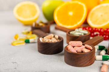 Obraz na płótnie Canvas Vitamins and supplements. Variety of vitamin tablets in a wooden spoon on a texture background.Multivitamins with fresh and healthy fruits.Food supplements. Flat lay. Space for text.Copy space