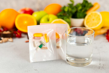 Vitamins and supplements. Variety of vitamin tablets with a glass of water on a texture background. Multivitamin complex for every day. Nutritional supplements. It's time to take your pills. Flat lay.