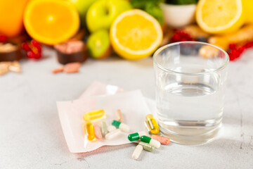 Vitamins and supplements. Variety of vitamin tablets with a glass of water on a texture background. Multivitamin complex for every day. Nutritional supplements. It's time to take your pills. Flat lay.