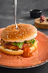 A delectable chicken burger topped with sweet and sour sauce, served on a plate for a satisfying meal