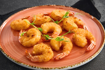 Crispy tempura shrimp elegantly arranged on a round ceramic plate, ready to be enjoyed, against a dark, textured background