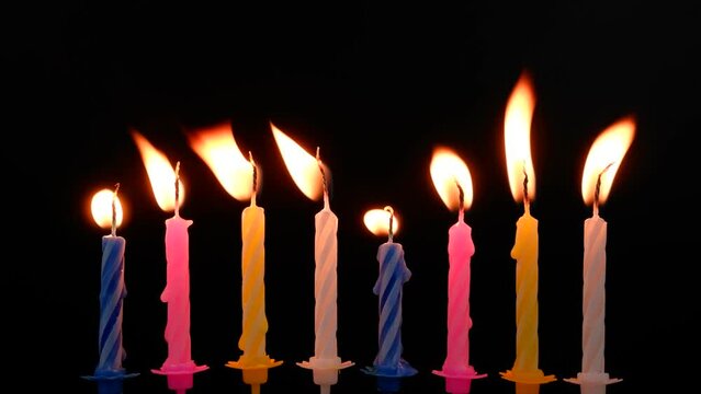 Birthday cake candles melting on black background.