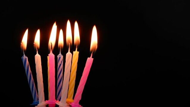 Birthday candles burning and melting on black background. Copy space for text.