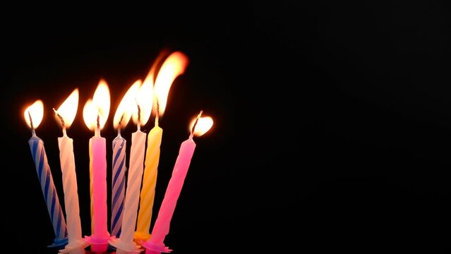 Many birthday candles burning and melting on black background. Copy space for text.