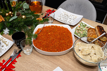 The table is set before Christmas dinner in Poland, with baked fish fillets in a carrot salad,...