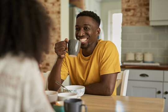 Smiling African man talking with his wife over coffee at breakfast