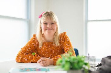 portrait of a girl with down syndrome drawing and smiling happily while enjoying development class