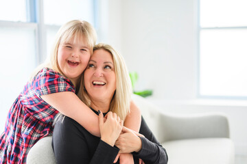 Mother and sweet down syndrome daughter girl at home sofa - obrazy, fototapety, plakaty