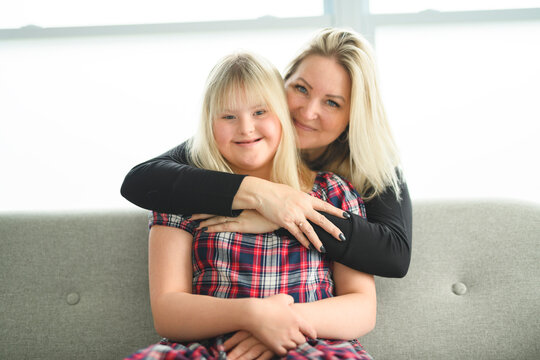 Mother and sweet down syndrome daughter girl at home sofa