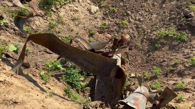 Deep explosion crater with mangled pieces from cluster shell, among an agricultural field, war in Ukraine