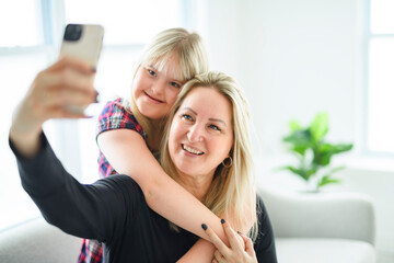 Mother and sweet down syndrome daughter girl at home sofa taking photo