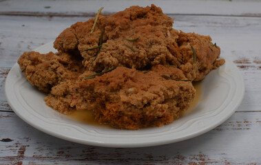 Cooked seitan on white plate, wooden table