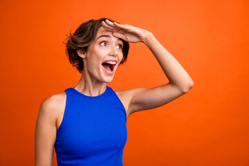 Profile photo of impressed cute cheerful lady arm touch forehead look away empty space ad isolated on orange color background