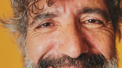 Close-up, the eye of an elderly gray-haired man looking at the camera with a smile