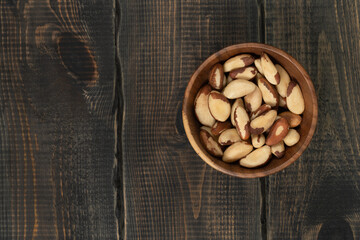 Peeled brazil nut in wooden cup on decorative wooden background