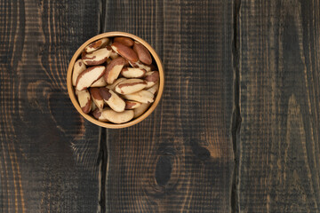 Peeled brazil nut in wooden cup on decorative wooden background