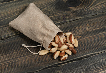 Peeled Brazil nuts in a jute bag on a decorative wooden background