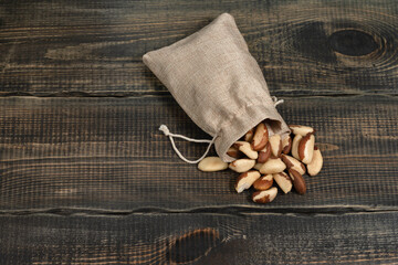 Peeled Brazil nuts in a jute bag on a decorative wooden background